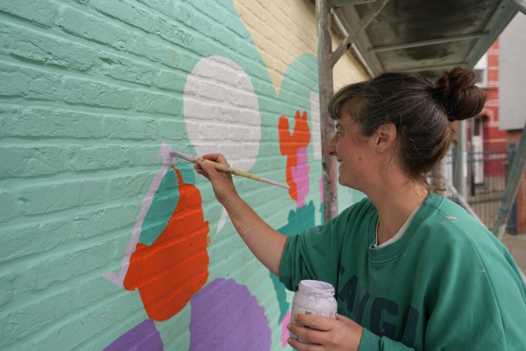 L'artiste Odile Brée peignant le mur de la commune de Berchem-Sainte-Agathe