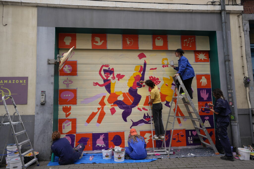 Collectif ton piquant peignant une fresque féministe sur la porte de garage d'Amazone