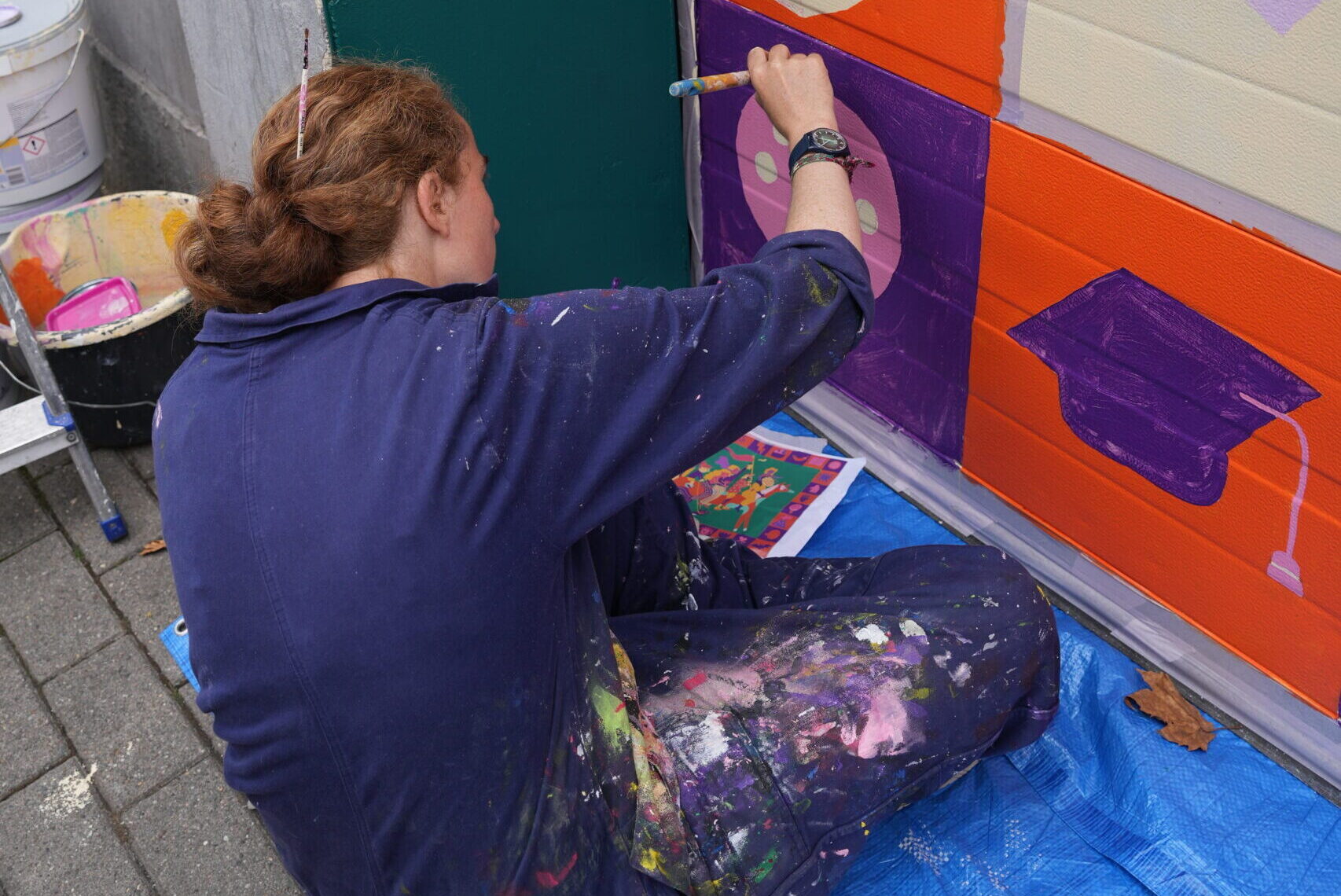 Collectif ton piquant peignant une fresque féministe sur la porte de garage d'Amazone